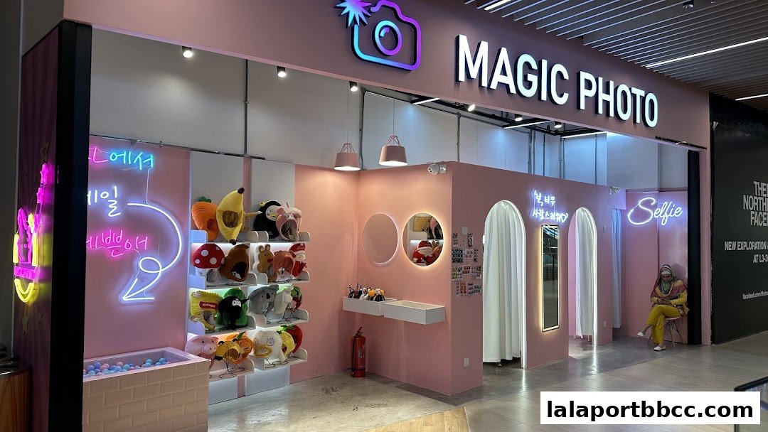 A brightly lit pink photo booth shop with plush toys and neon signs.