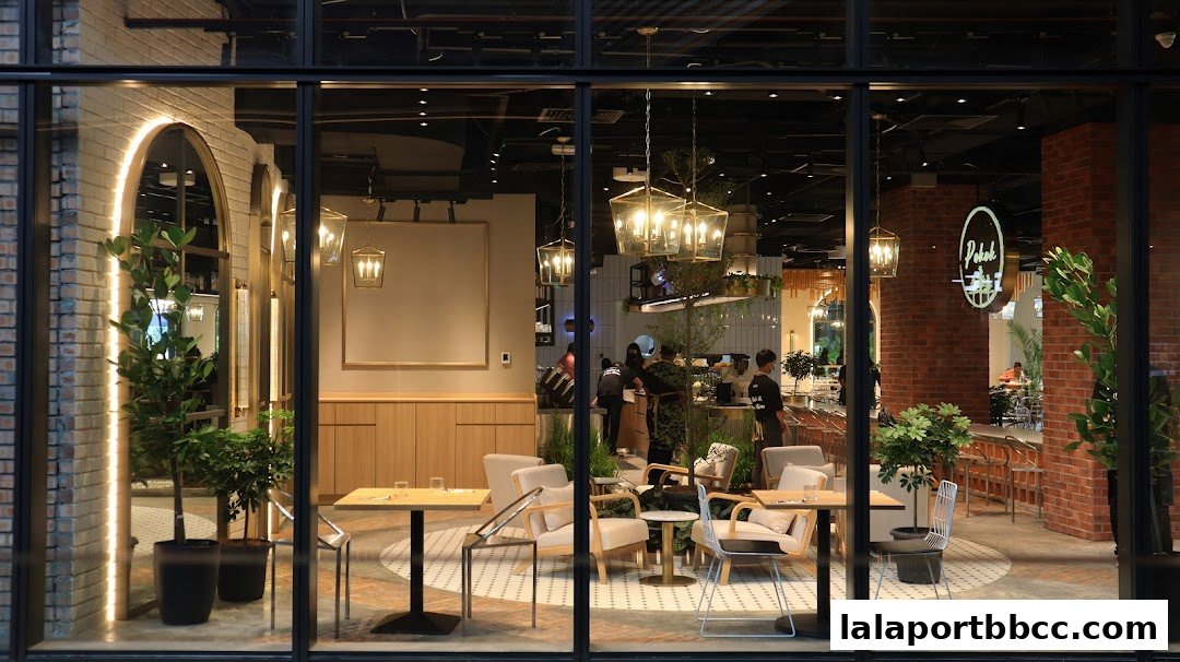 Interior view of a modern cafe with seating, plants, and staff behind the counter.