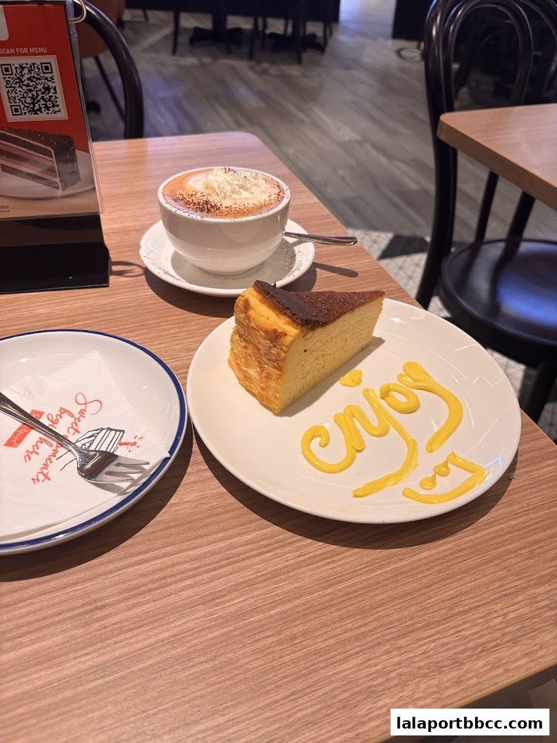 A slice of cheesecake and a coffee with whipped cream on a table.