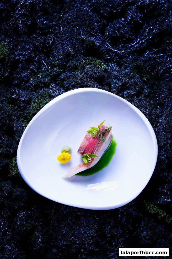 A beautifully plated dish with sliced meat, green sauce, and a yellow flower on a white plate.