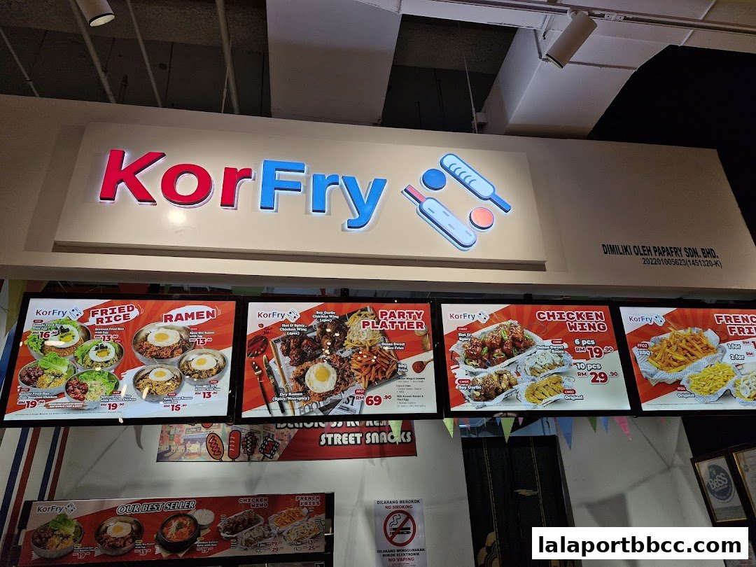 A brightly lit KorFry shop front displaying various Korean fried chicken and street snack menu items.