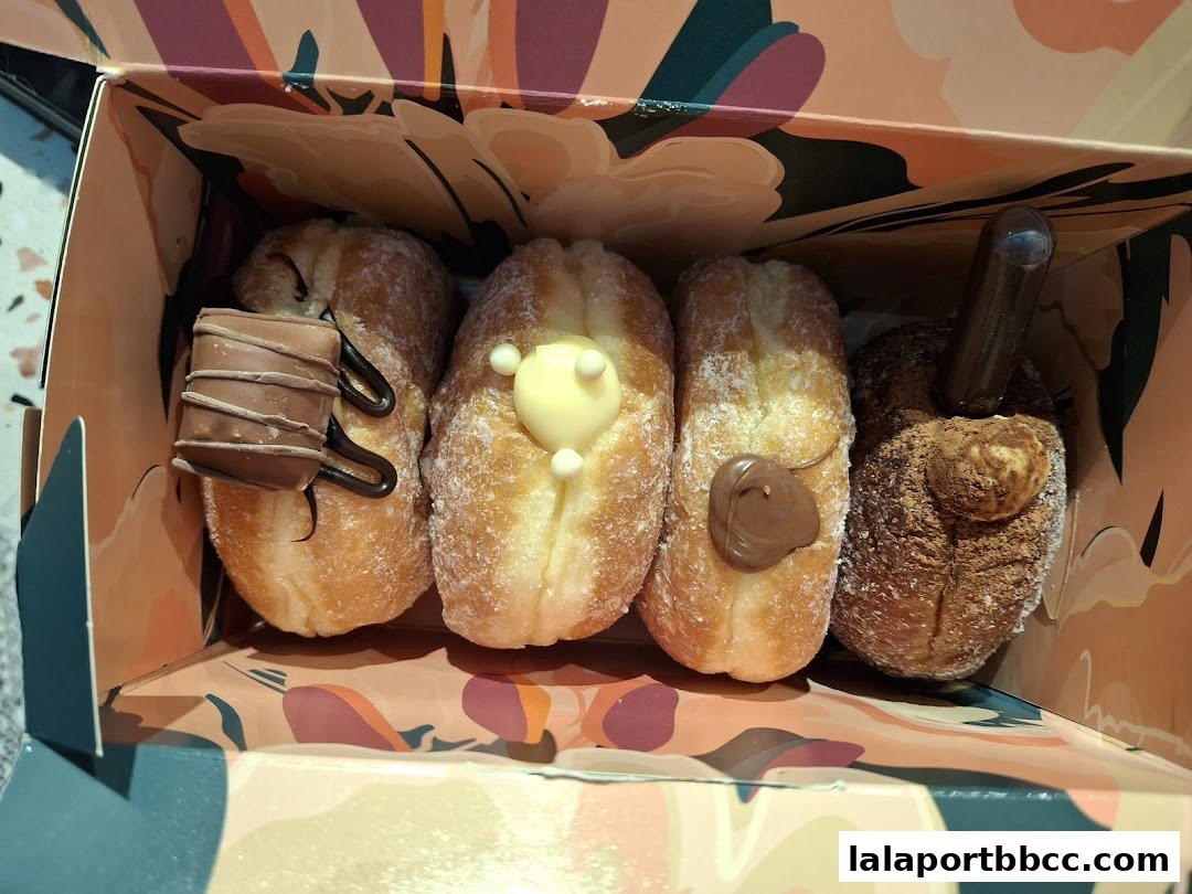 A box of four assorted donuts with various toppings and fillings.