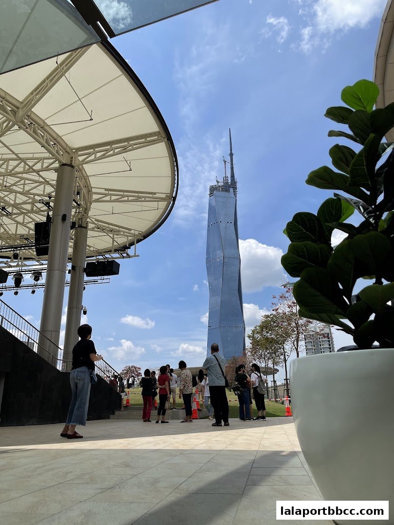 People gather outdoors with a distinctive skyscraper in the background.