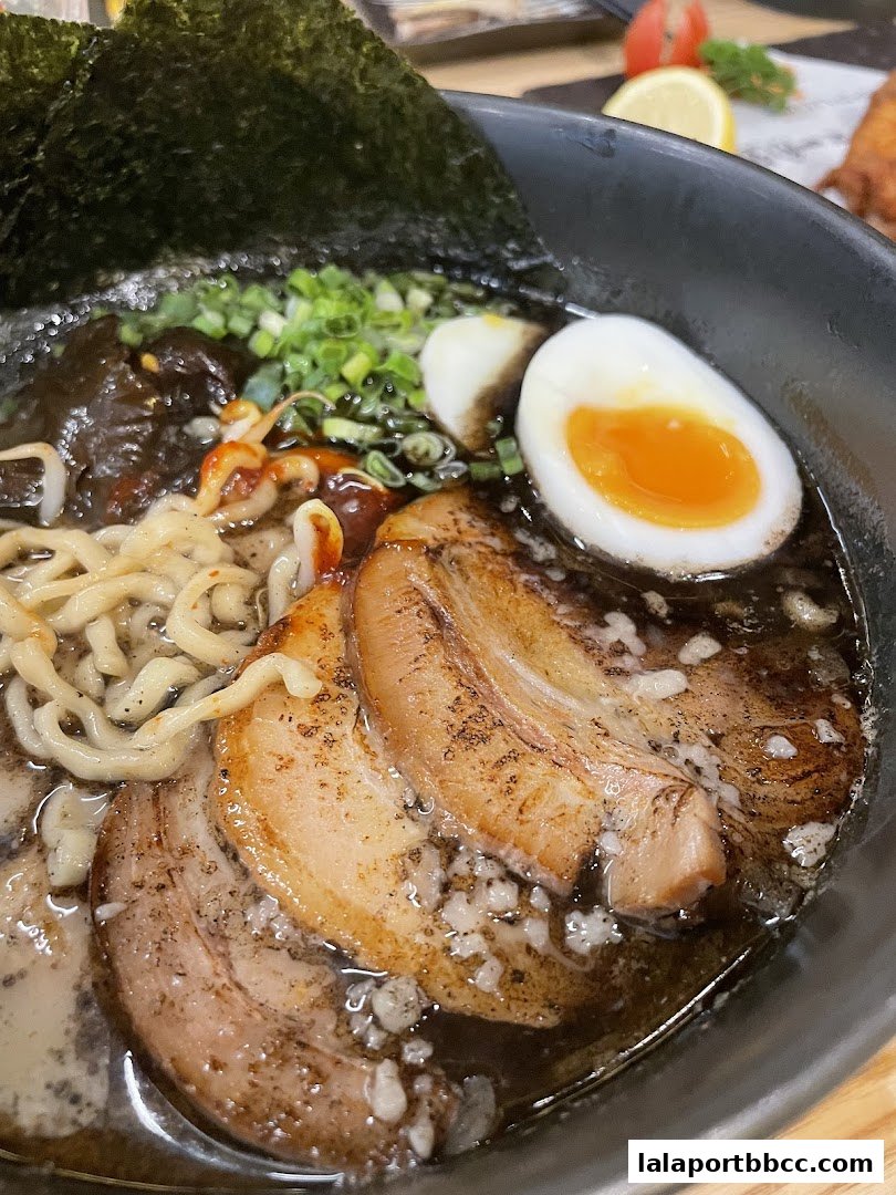 A close-up of a delicious bowl of ramen with chashu pork, egg, and nori.