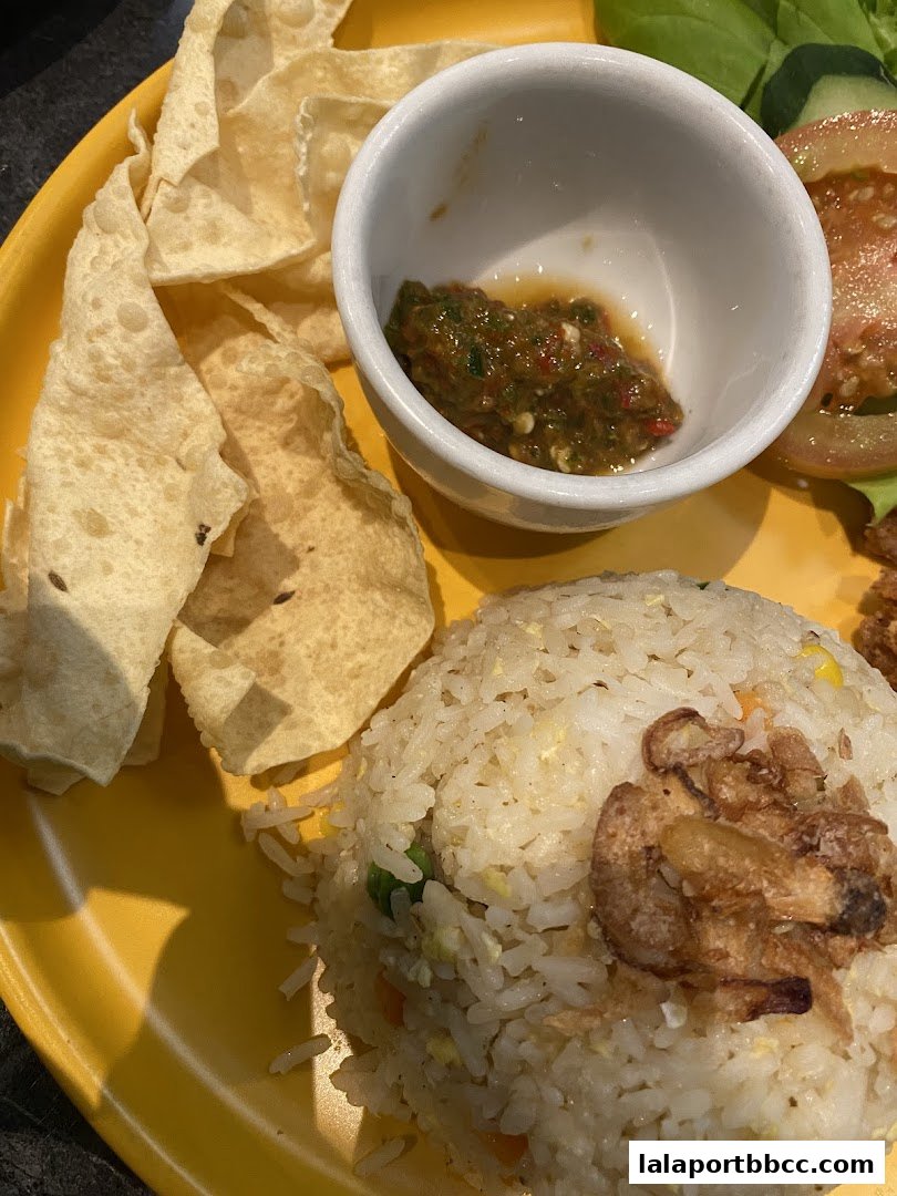 A close-up of a delicious meal featuring fried rice, papadums, and a spicy dipping sauce.