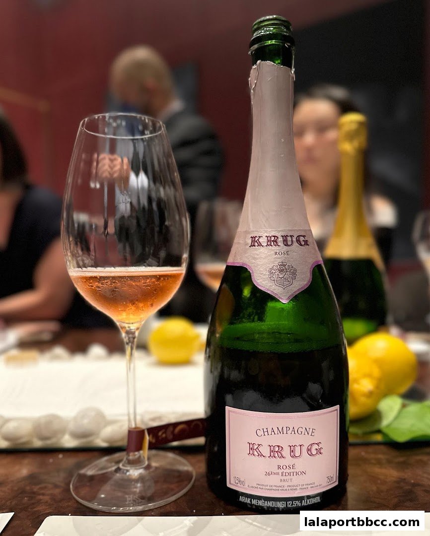 A glass of rosé champagne sits next to a bottle of Krug Rosé champagne.