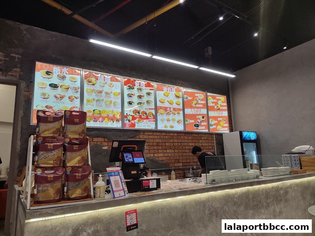 A dessert shop counter with illuminated menus displaying various sweet treats and a staff member preparing orders.
