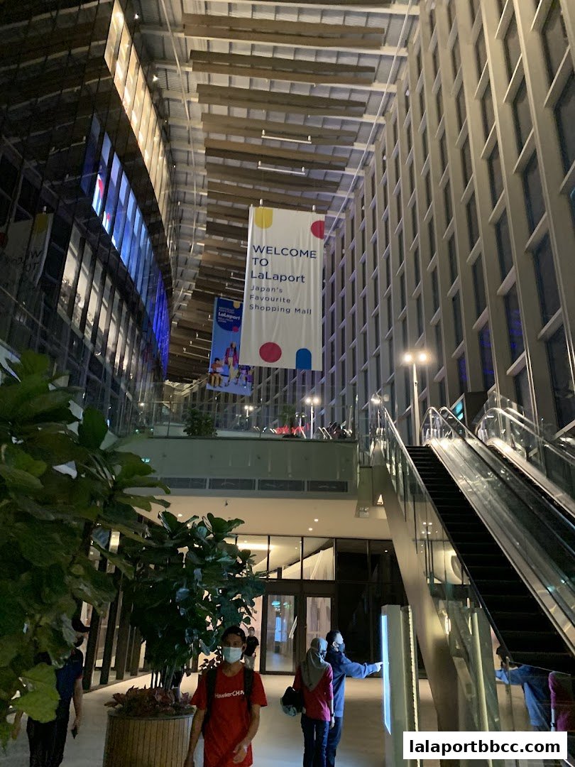 Interior view of a modern shopping mall with escalators and banners.