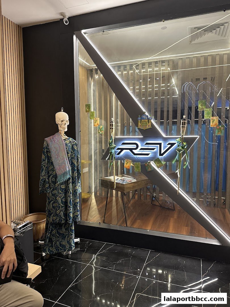 A skeleton mannequin dressed in traditional attire stands outside a modern shop with a prominent logo.