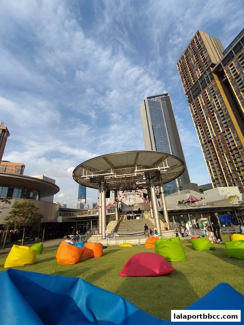 Outdoor seating area with colorful beanbags in front of a stage and modern buildings.