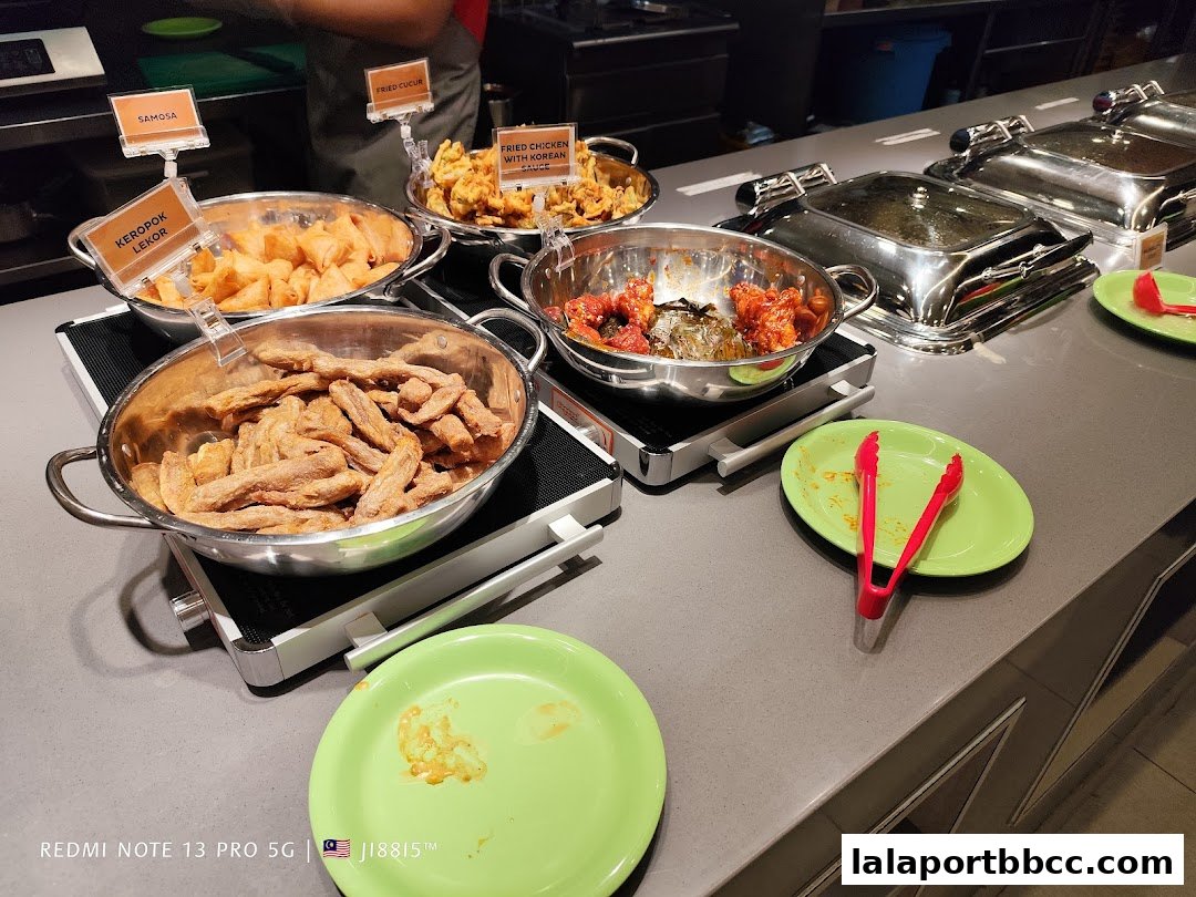 A buffet spread featuring various fried snacks and dishes, including samosas and Korean fried chicken.