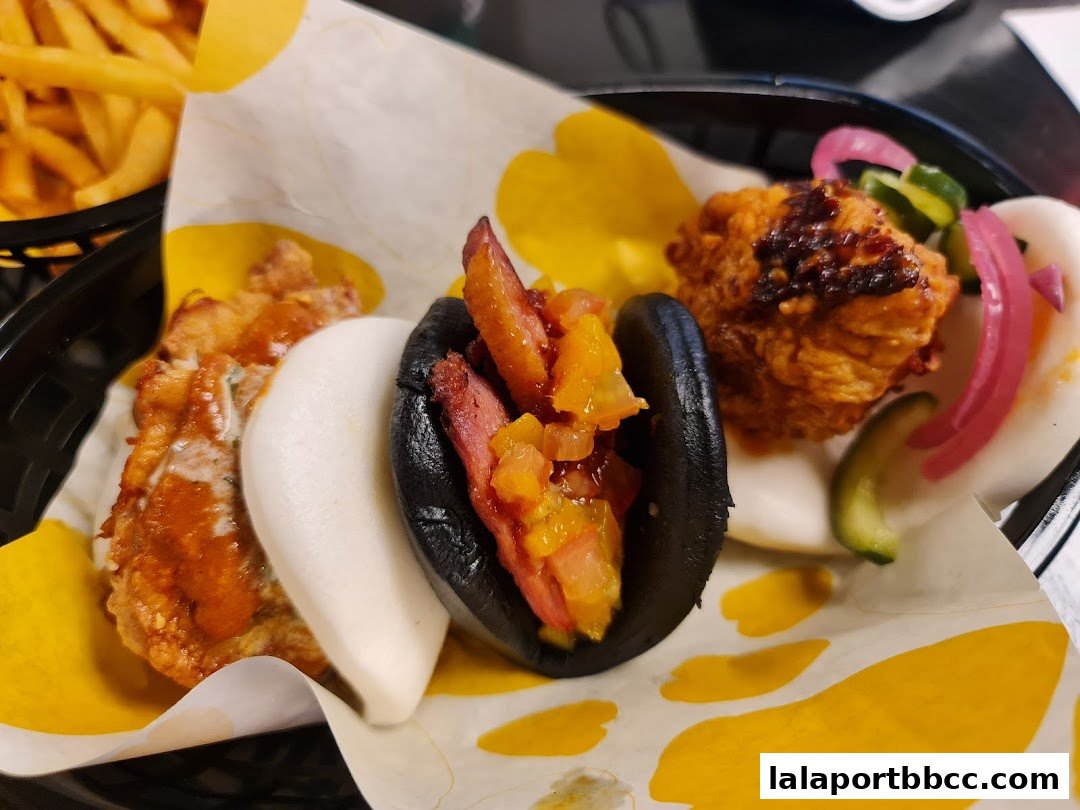 A close-up shot of delicious bao buns with various fillings and a side of fries.