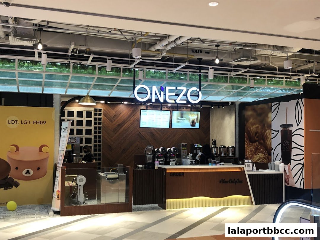 A modern cafe counter with a prominent 'ONEZO' sign and digital menu displays.