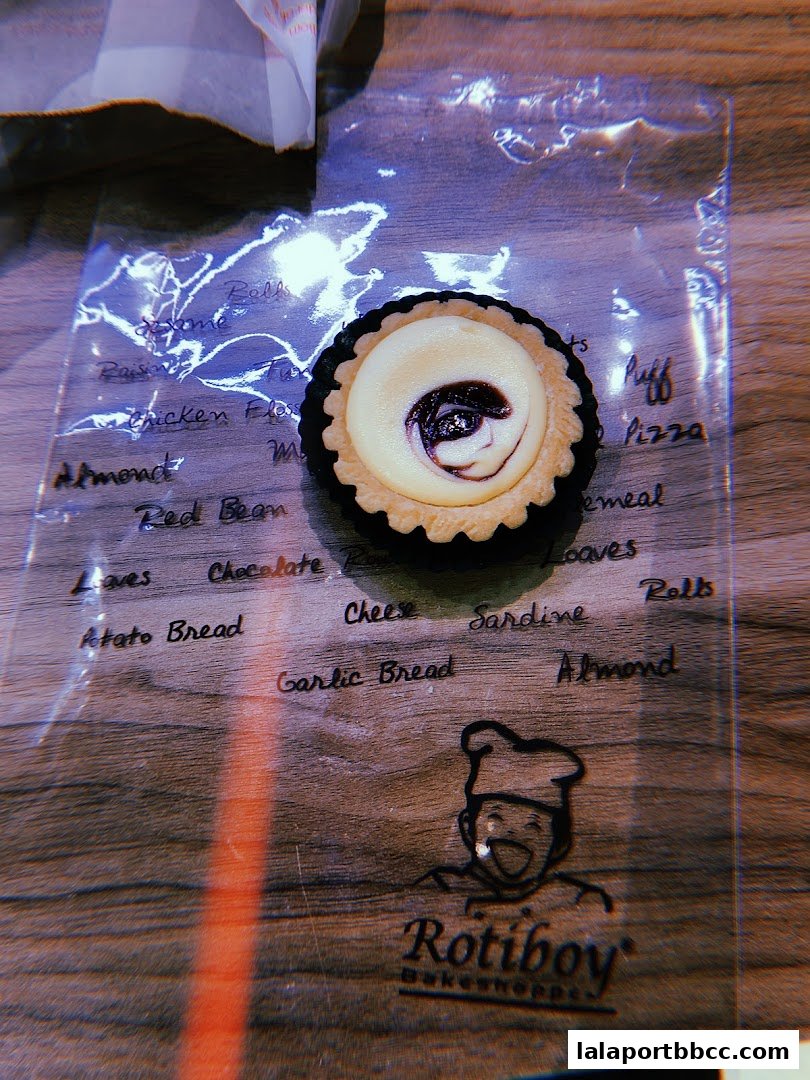 A close-up of a Rotiboy pastry with a list of potential flavors written on plastic.