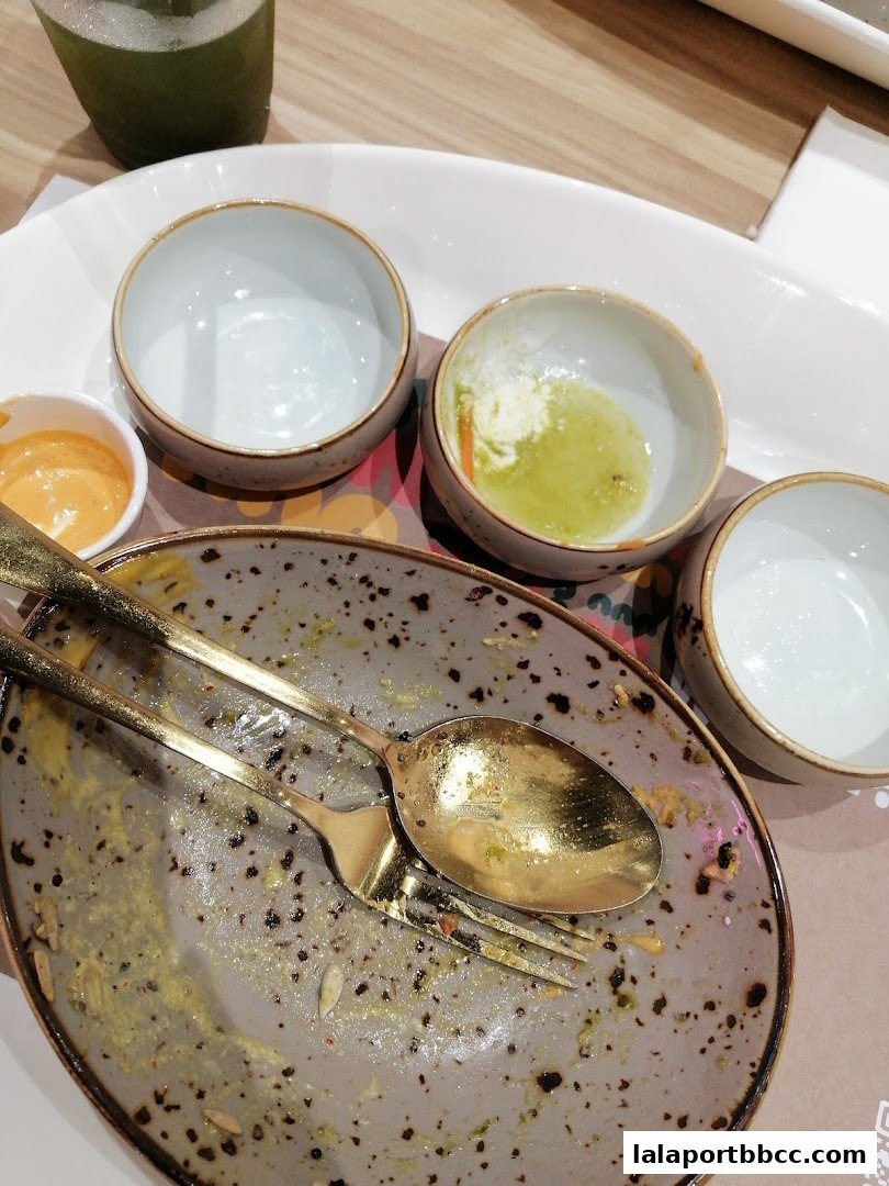 A close-up of a dirty plate with cutlery and small bowls after a meal.