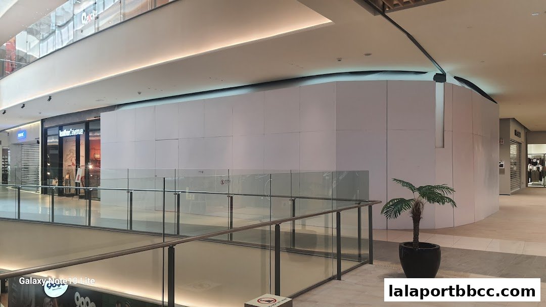 A view of a shopping mall interior with a shop front covered by white panels.