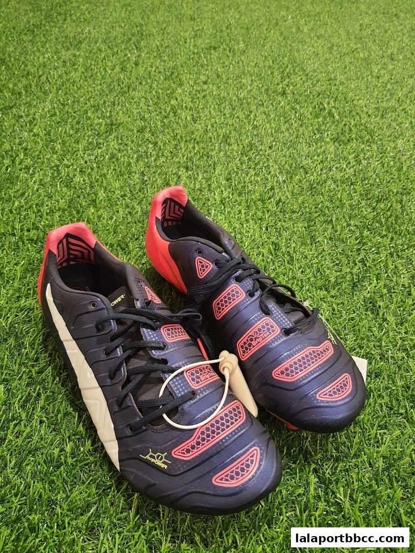 A pair of dark blue Puma soccer cleats with pink accents on a green grassy surface.