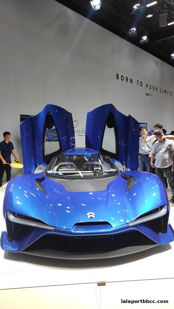 A striking blue electric sports car with its doors open, displayed at an exhibition.