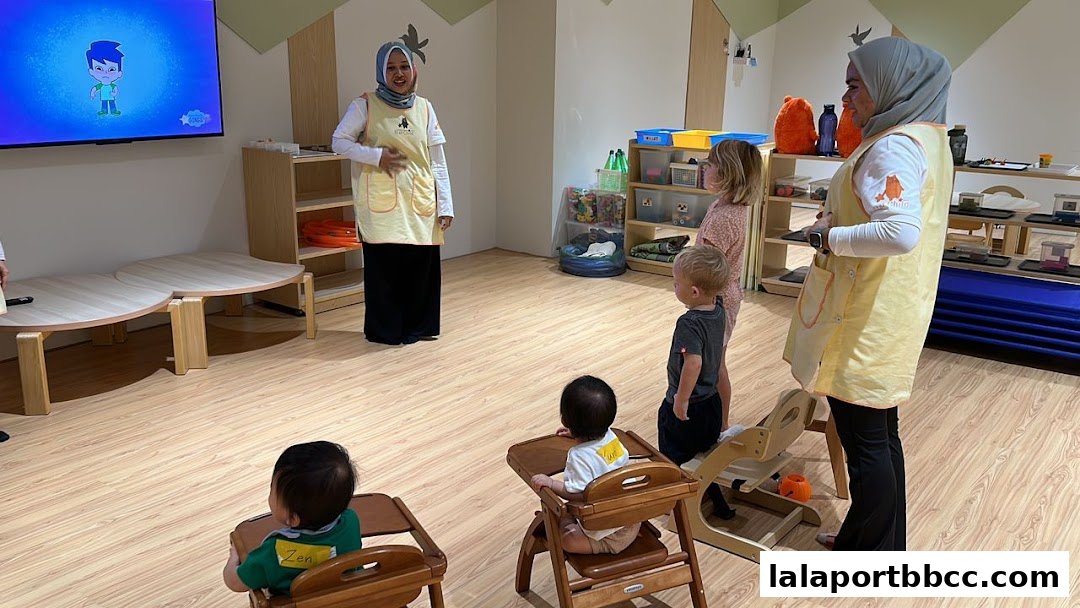 Teachers interacting with children in a brightly lit childcare center classroom.