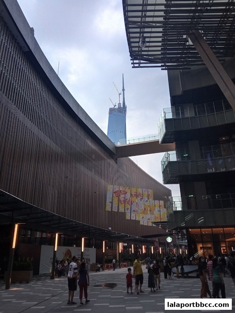 People walking in a modern plaza with a tall building under construction in the background.