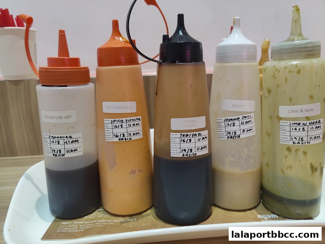 A selection of sauce bottles with labels indicating flavors and preparation dates.