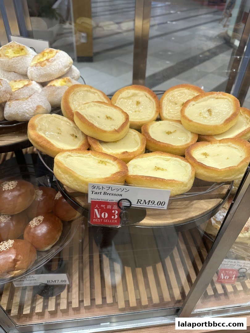 A display of freshly baked pastries, including Tsubu Anpan and Tart Bresson, with prices clearly marked.