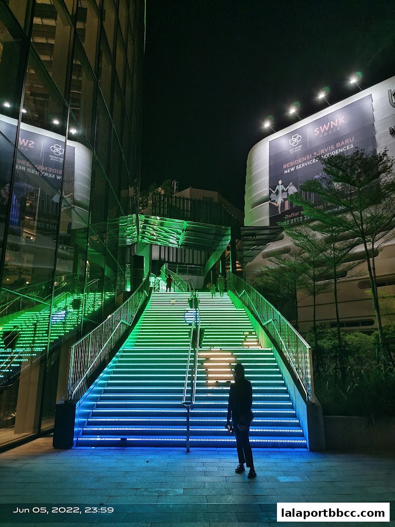 A person stands at the bottom of a brightly lit staircase at night.