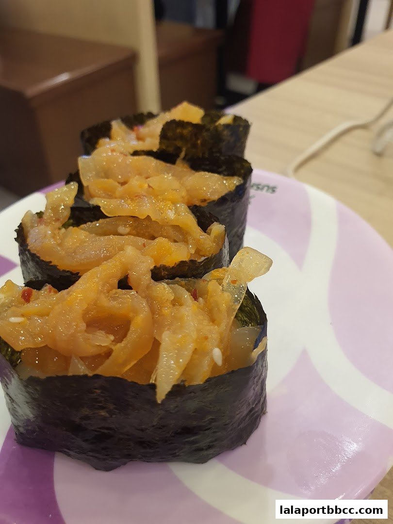 Close-up of three pieces of sushi with a spicy jellyfish topping on a patterned plate.