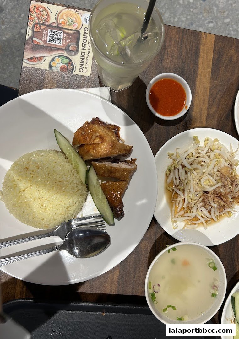 A delicious plate of chicken rice with a side of bean sprouts and a refreshing drink.