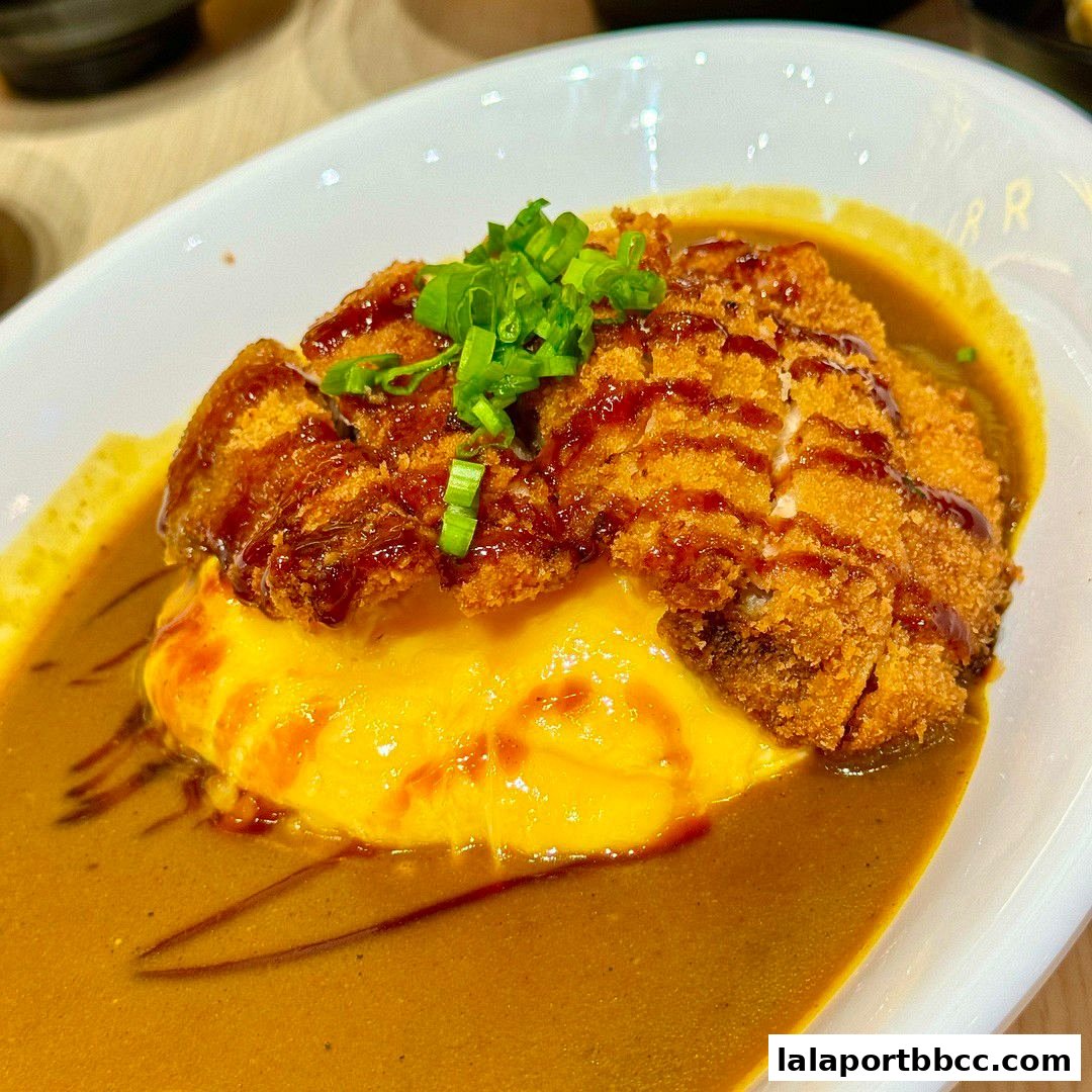 A close-up of a delicious Japanese curry dish with crispy fried chicken and fluffy omelet.