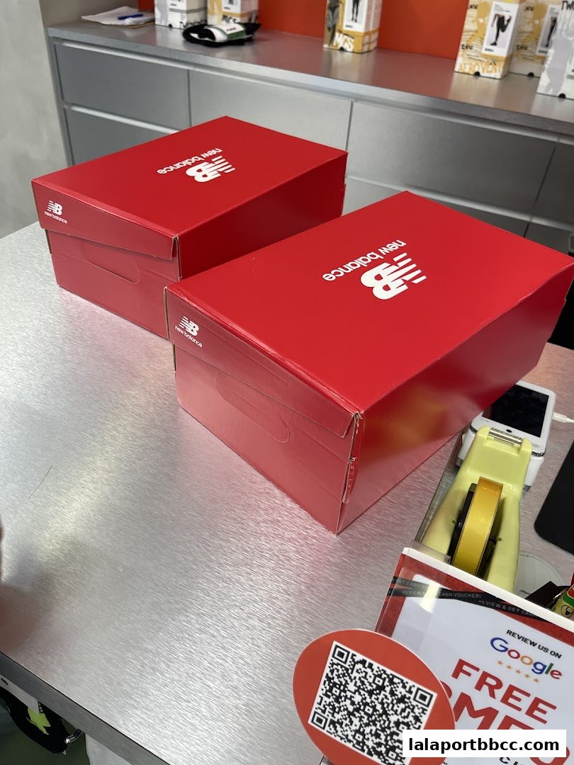Two red New Balance shoe boxes are displayed on a metallic counter.