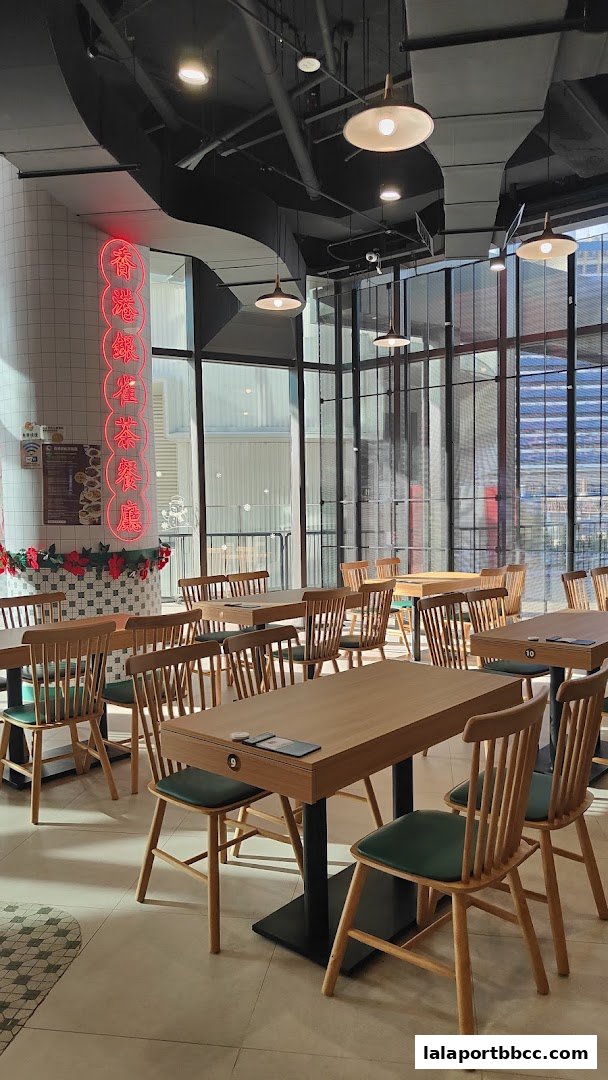 Interior of a modern restaurant with wooden tables and chairs, illuminated by pendant lights.