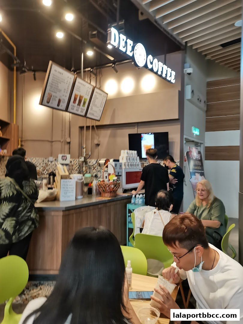 Customers enjoy drinks at Dee Coffee, a modern cafe with illuminated signage.