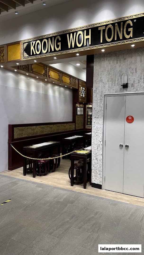 The entrance to Koong Woh Tong, a traditional Chinese herbal shop, with seating and decorative elements.