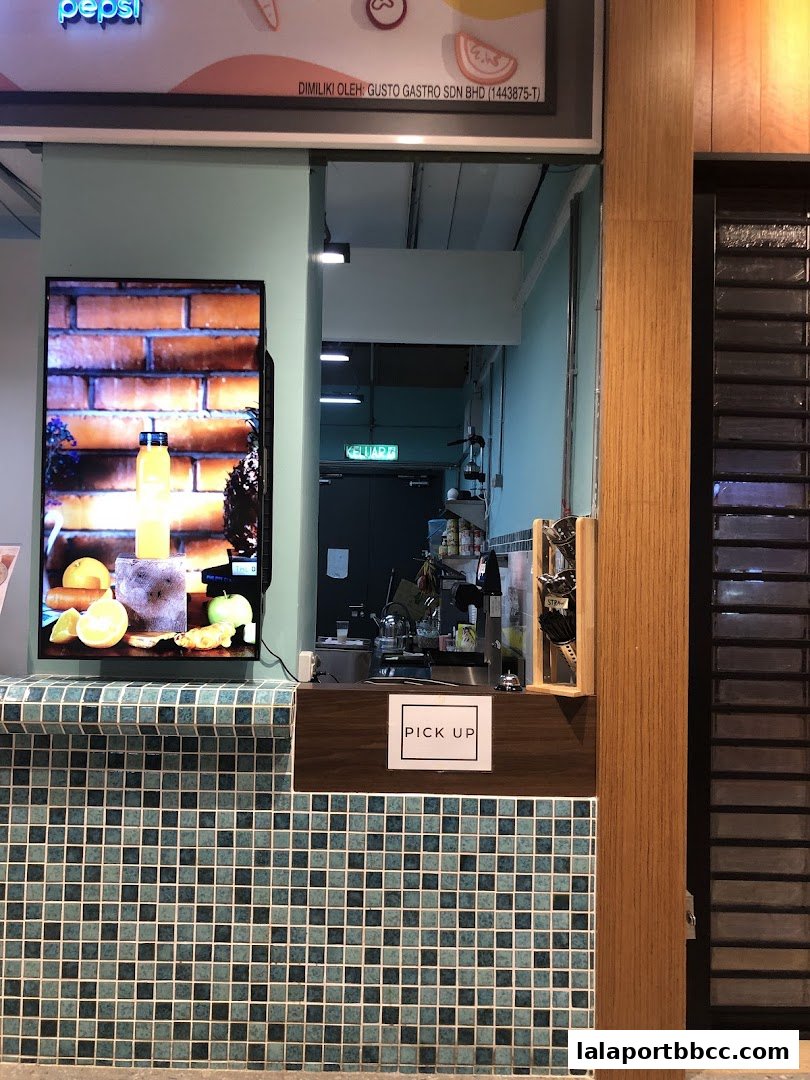 A counter with a 'Pick Up' sign and a screen displaying juice and fruits.