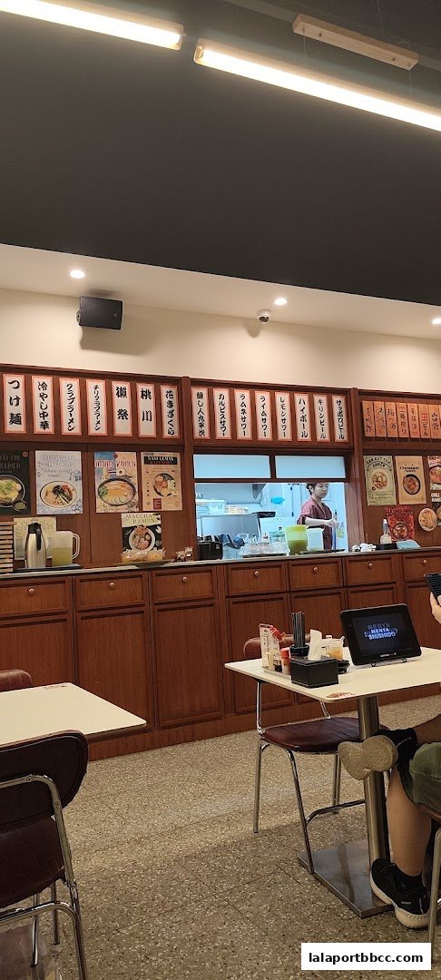 Interior view of a ramen shop with Japanese menu items displayed on the wall.