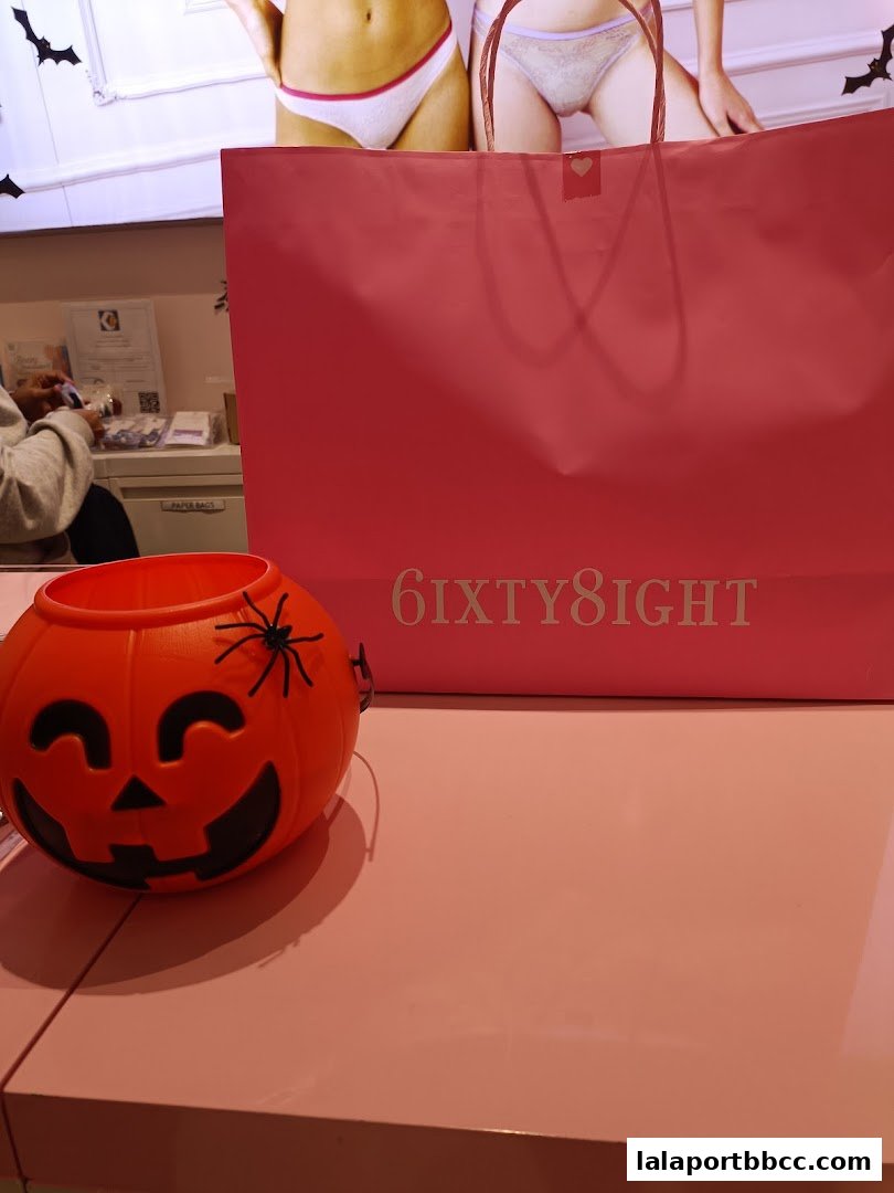 A pink shopping bag with the 6IXTY8IGHT logo and a Halloween pumpkin decoration.