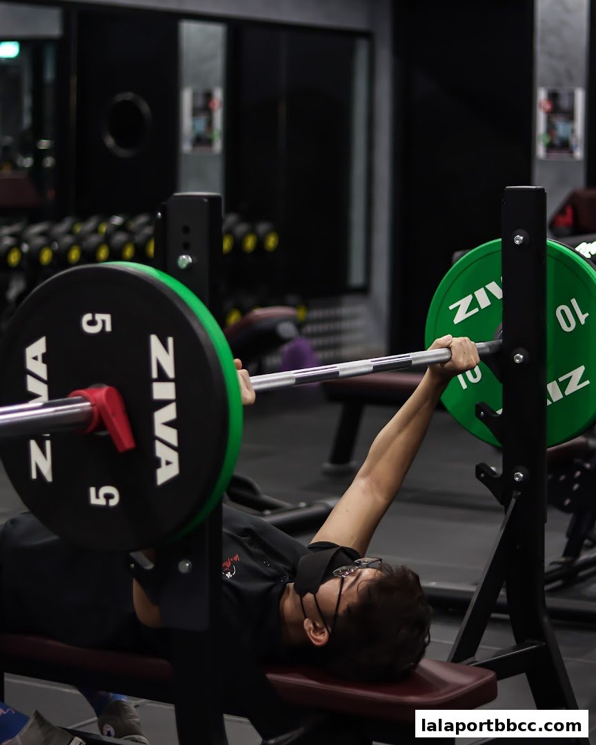A person performing a bench press with weight plates in a gym.