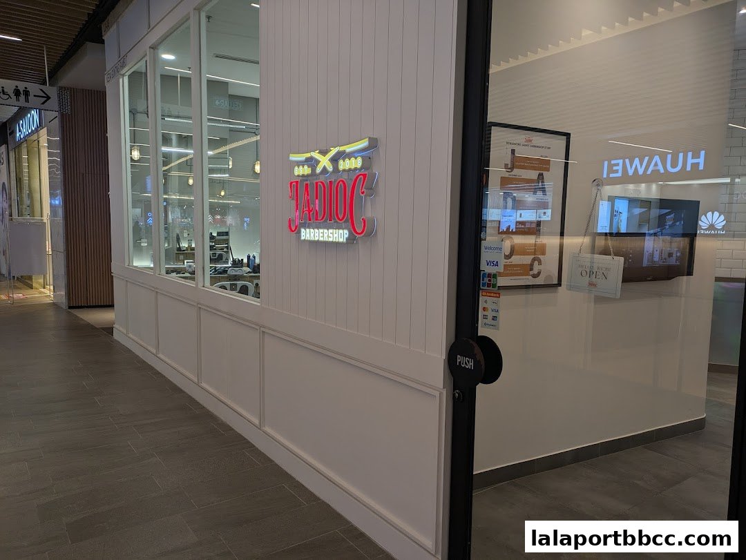 The entrance to Jadioc Barbershop with its illuminated sign and a 'Hello, We're Open' sign.