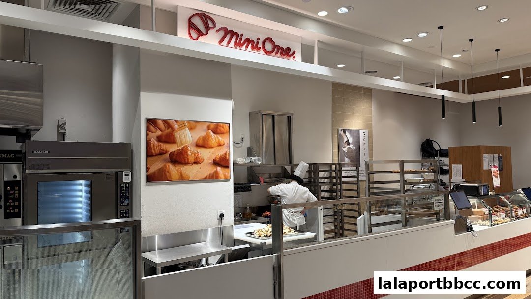 A bakery interior with a chef preparing food and display cases filled with baked goods.