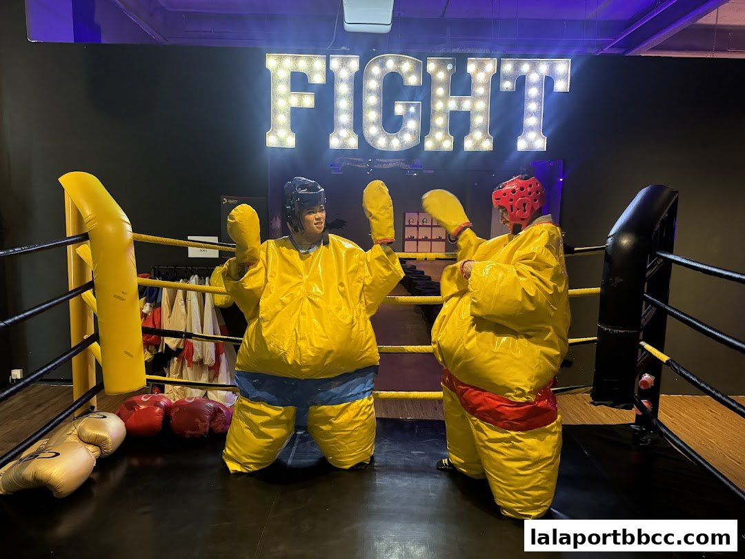 Two people in sumo suits ready to wrestle in a boxing ring.