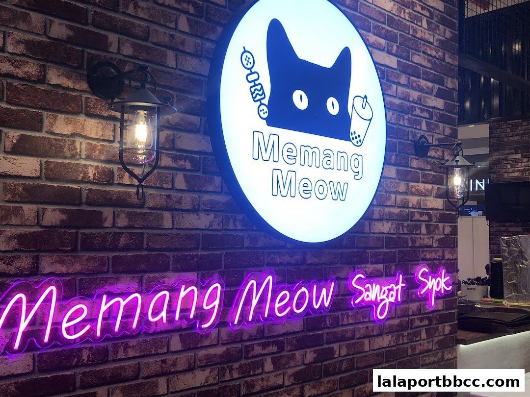 A brick wall with a glowing cat logo and neon sign for 'Memang Meow'.