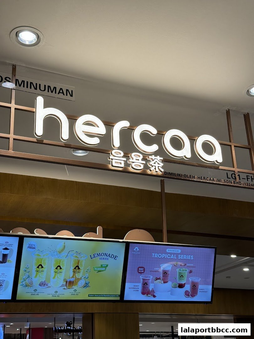 A brightly lit shop sign for Hercaa with illuminated text and a display of beverages.
