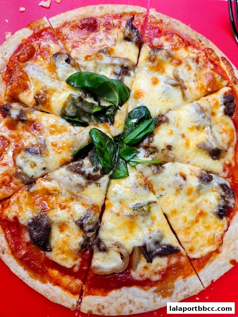 A delicious pizza topped with cheese, mushrooms, and fresh basil, sliced and ready to eat.