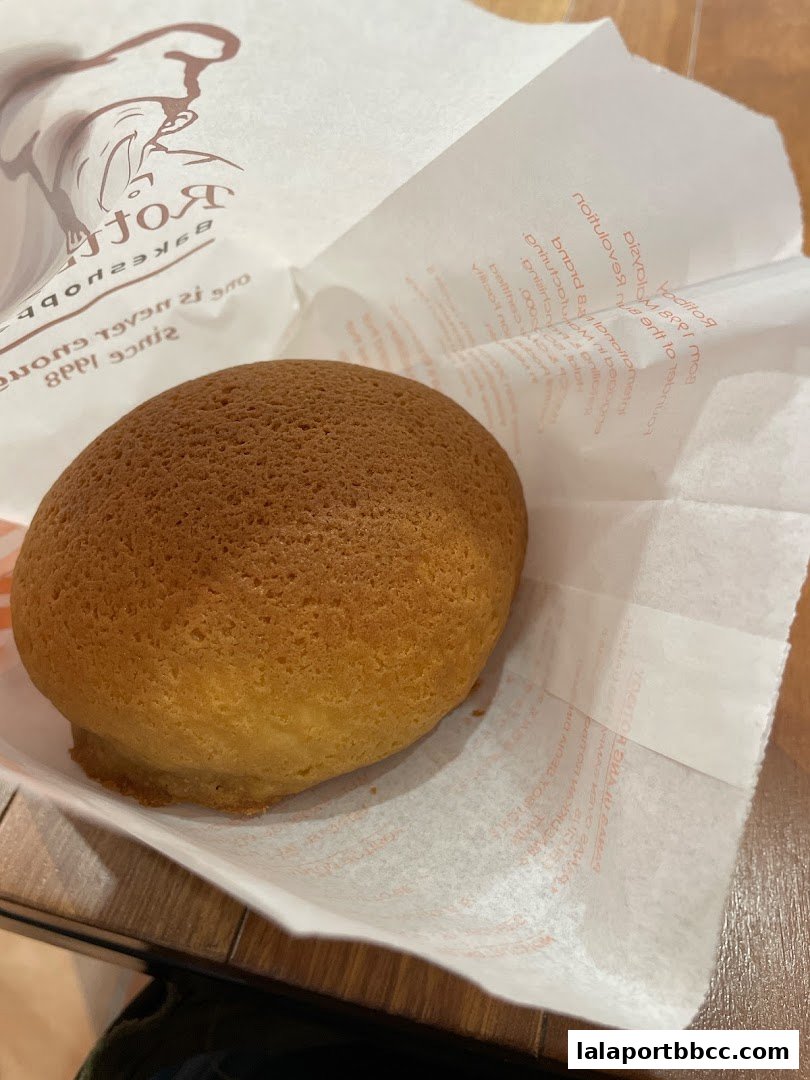 A close-up of a golden-brown Rotiboy bun in its branded paper packaging.