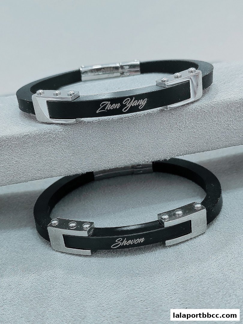 Two black silicone bracelets with silver accents, each engraved with a name.