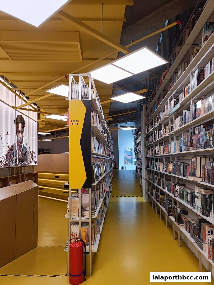 A wide aisle lined with bookshelves in a modern bookstore with yellow flooring.