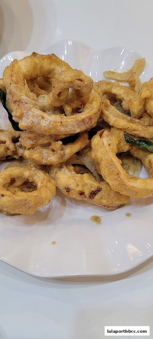A close-up shot of crispy, golden-brown calamari rings served on a white plate.
