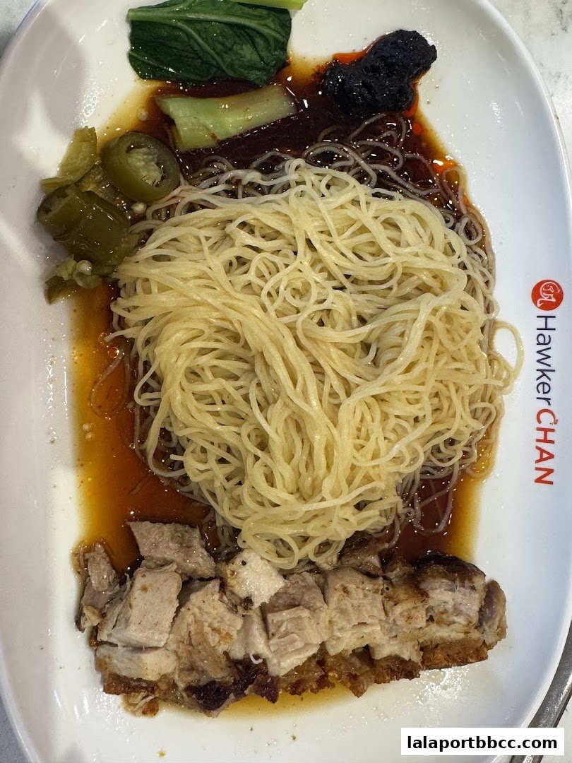 A plate of delicious noodles with roasted pork and vegetables, branded with Hawker Chan.