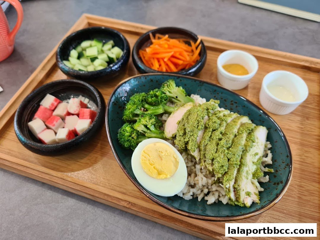 A healthy meal featuring sliced chicken with green sauce, rice, broccoli, egg, and side dishes.